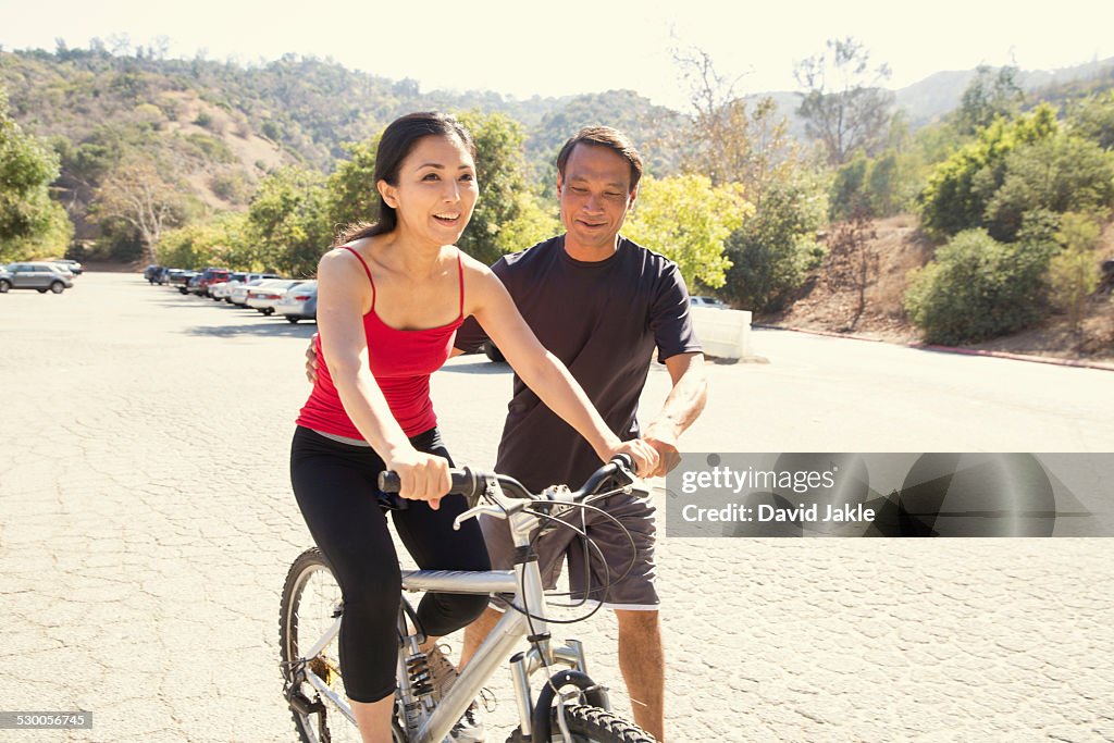 Mature woman learning to ride bicycle in park