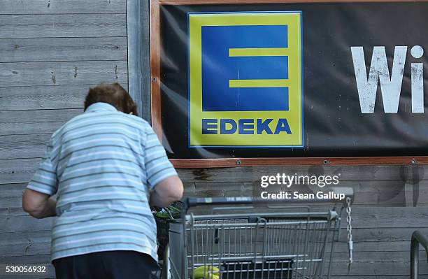 An elderly woman loads her purchases into a bicycle basket outside an Edeka supermarket on May 10, 2016 in Berlin, Germany. German anti-cartel...