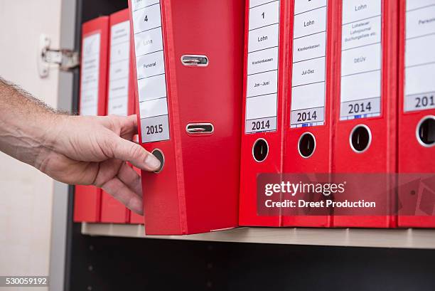 man taking confidential file from filing cabinet, munich, bavaria, germany - file cabinet stock-fotos und bilder