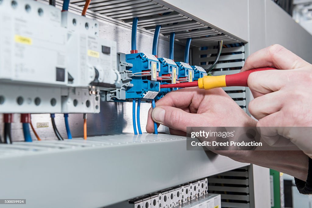 Close-up of electrician screwing cable in distribution fusebox, Munich, Bavaria, Germany