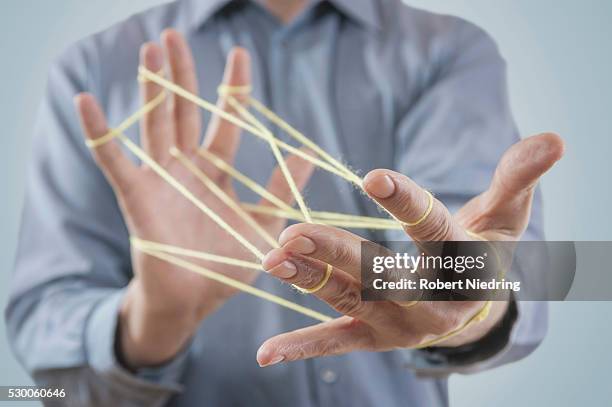 mid section view of a man's hands making a cats cradle with string, bavaria, germany - mani fili foto e immagini stock
