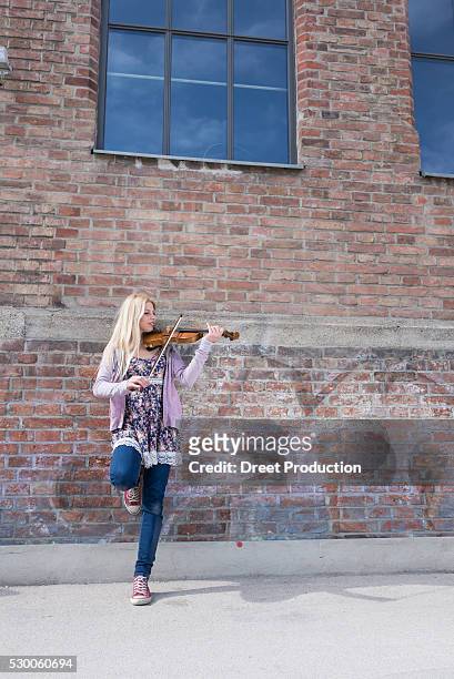 caucasian teenage girl playing violin in front of brick wall, munich, bavaria, germany - bavaria girl stockfoto's en -beelden