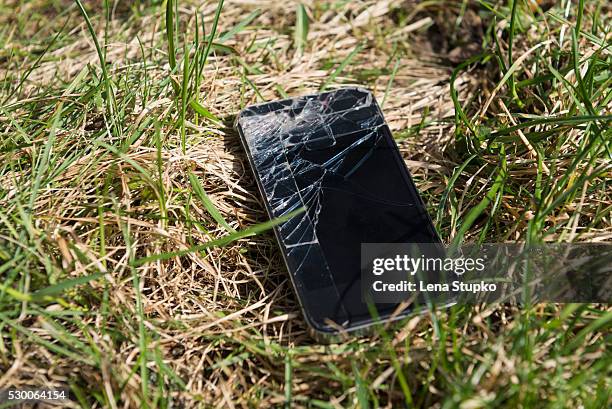 close-up of smartphone with cracked screen lost in grassy field, bavaria, germany - broken smartphone fotografías e imágenes de stock