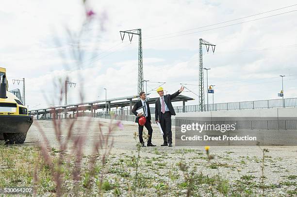 two businessmen with hard hats on construction site - architekt mit plan frontal stock-fotos und bilder