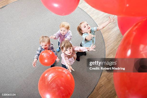 four kids playing with red balloons in kindergarten, elevated view - nursery school building stock pictures, royalty-free photos & images