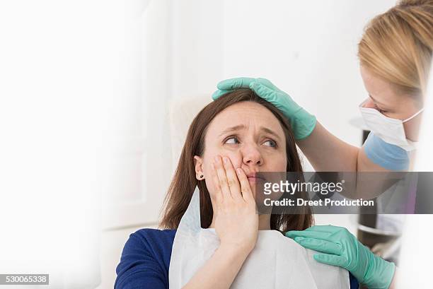 female doctor consoling patient suffering from toothache, munich, bavaria, germany - tandpijn stockfoto's en -beelden