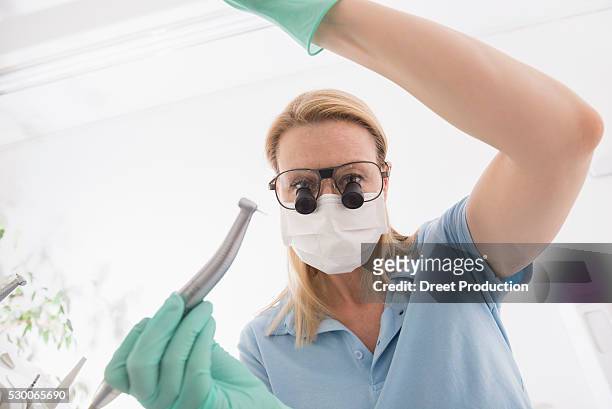 close-up of female dentist holding dental drill with magnifiers on eyeglasses, munich, bavaria, germany - tandartsboor stockfoto's en -beelden