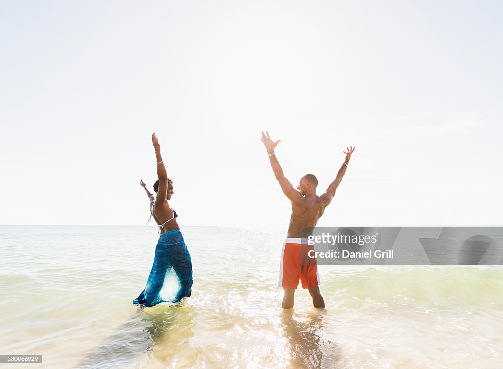 USA, Florida, Jupiter, Mature couple standing in sea with arms raised