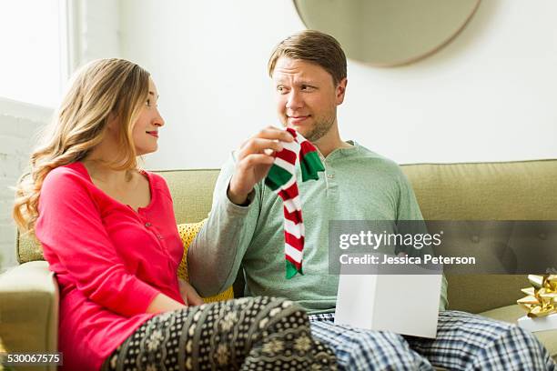 man holding unwanted christmas gift - socks fotografías e imágenes de stock