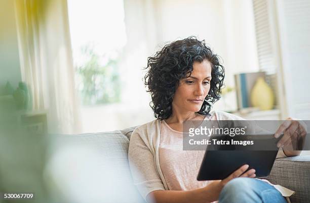 usa, new jersey, jersey city, woman using digital tablet on sofa - mature reading computer bildbanksfoton och bilder