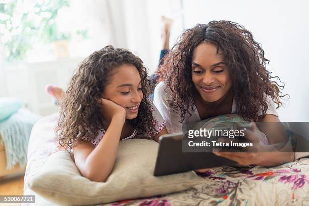 usa, new jersey, jersey city, mother with daughter (8-9) using digital tablet on bed - watching ipad stock pictures, royalty-free photos & images