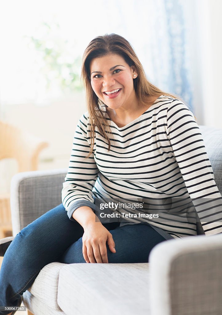 USA, New Jersey, Jersey City, Portrait of happy woman sitting on sofa