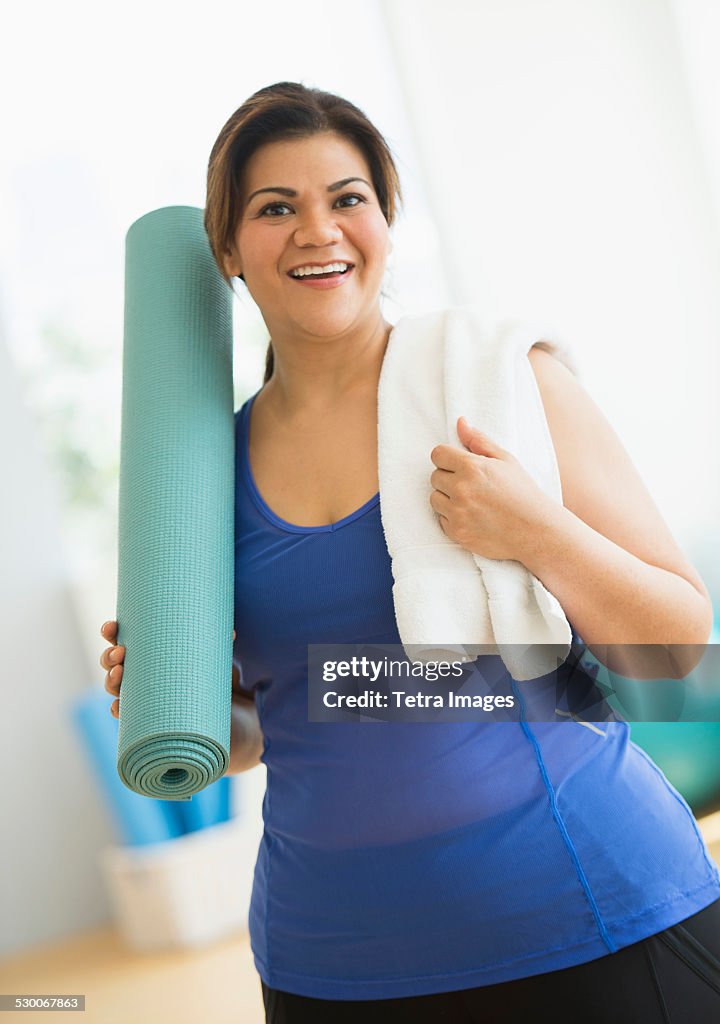 USA, New Jersey, Jersey City, Woman holding exercise mat at gym