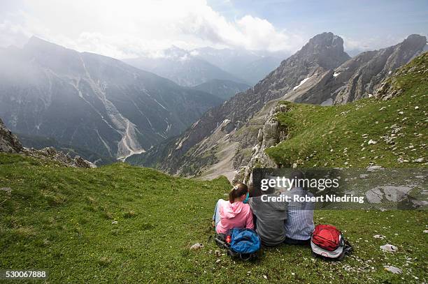 father and kids looking at hiking map mountains - karwendel stock-fotos und bilder