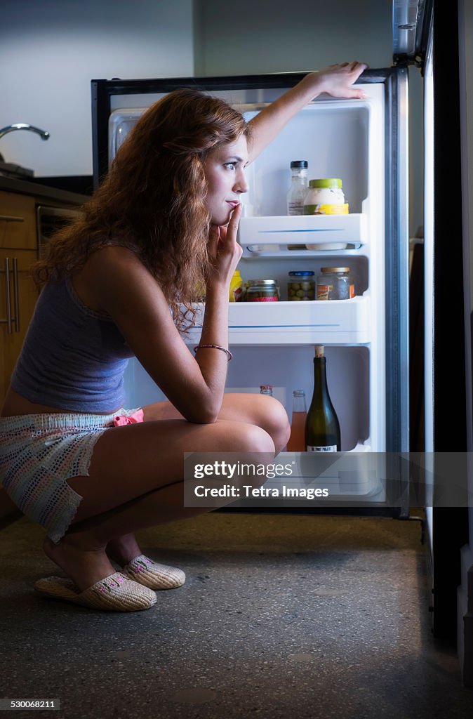 USA, New Jersey, Jersey City, Young woman looking into refrigerator