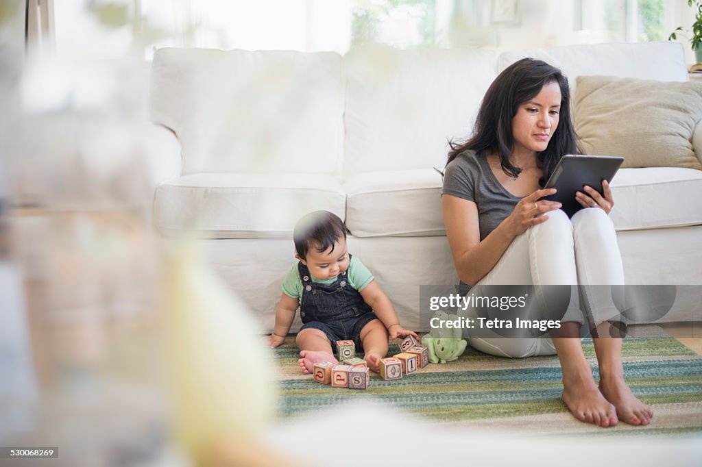 USA, New Jersey, Jersey City, Mother using tablet pc while her son (6-11 months) playing with building blocks