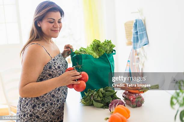 usa, new jersey, jersey city, woman taking out vegetables of grocery bag - grasso nutrienti foto e immagini stock