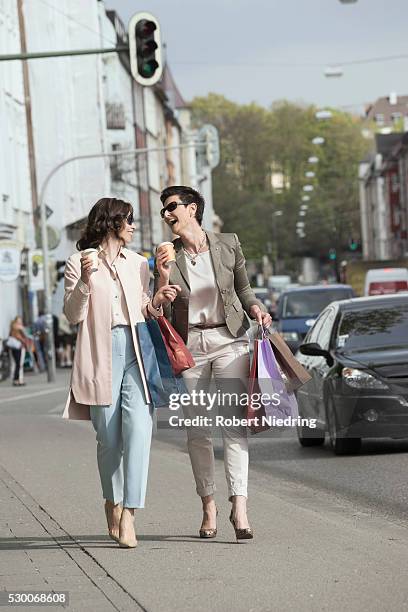 two mature women shopping in the city with coffee, bavaria, germany - オーバーコート ストックフォトと画像