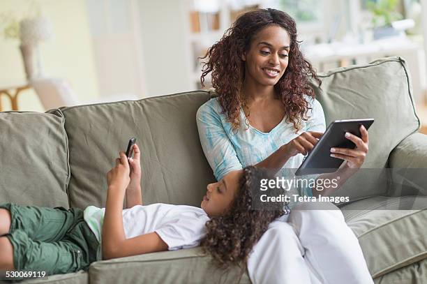 usa, new jersey, jersey city, mother and daughter (8-9) relaxing on sofa - new jersey home stock pictures, royalty-free photos & images