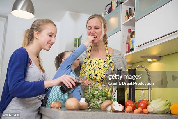 mother and daughter flavor salad while son feeding mother - vinegar stockfoto's en -beelden