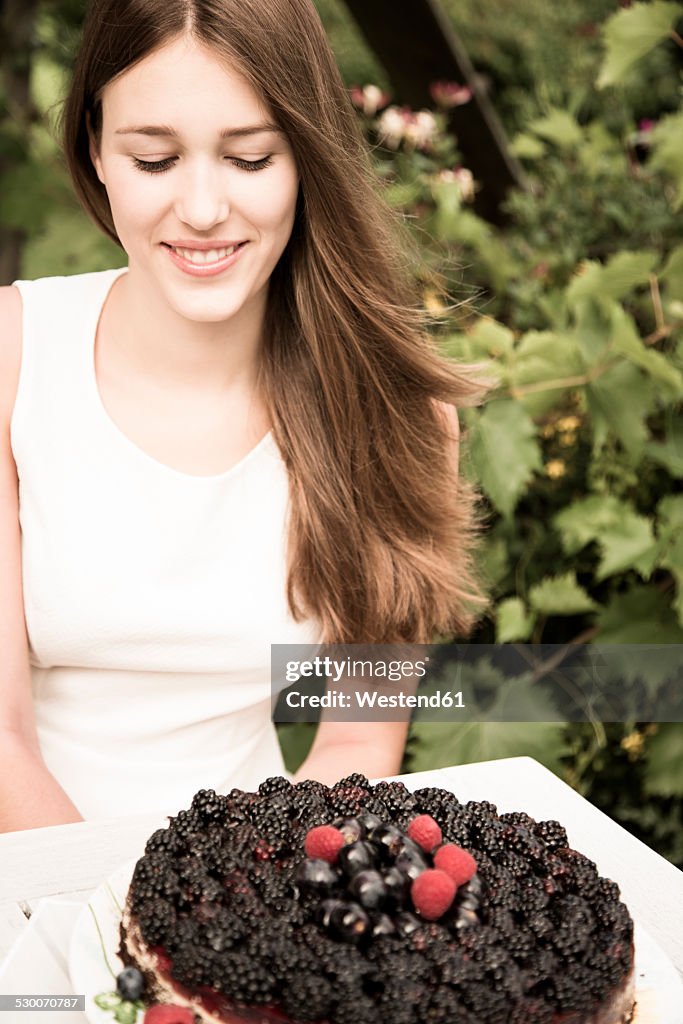 Portrait of young woman with chocolate berry cake