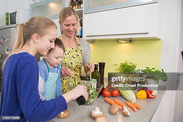 mother and children preparing salad in kitchen, smiling - vinegar stockfoto's en -beelden