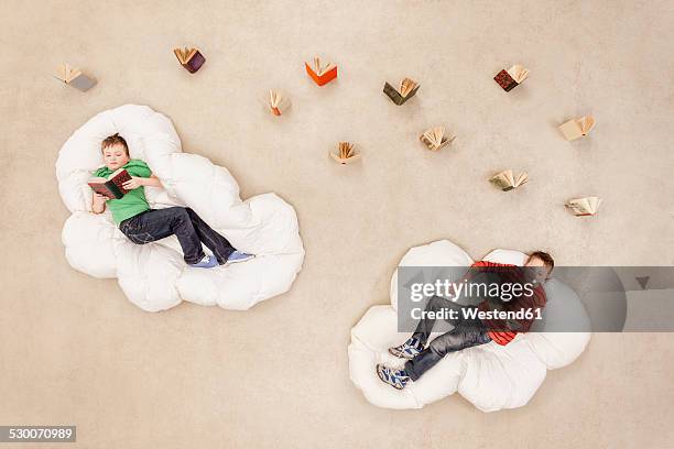 boys lying on clouds, reading - escapism reading stock pictures, royalty-free photos & images