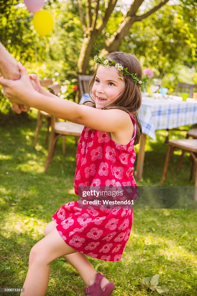 Girl pulling adult's arm in garden