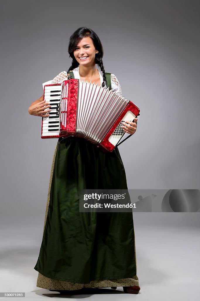 Portrait of young woman with accordion wearing dirndl