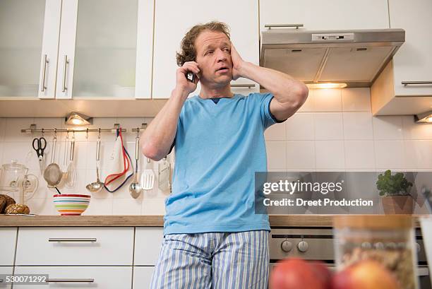 serious man on cell phone in kitchen - küche überrascht mann stock-fotos und bilder