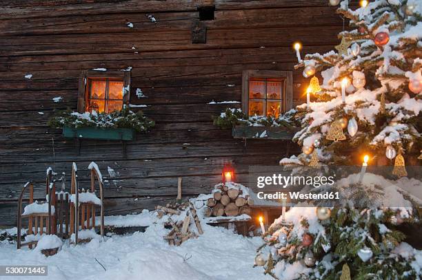 austria, salzburg state, altenmarkt-zauchensee, facade of wooden cabin with lightened christmas tree in the foreground - winter candlelight stock pictures, royalty-free photos & images