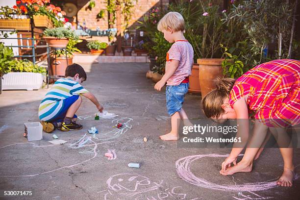 germany, northrhine westphalia, bornheim, children playing and drawing in courtyard - mensch kreide stock-fotos und bilder