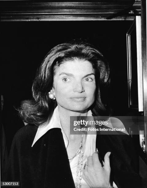 Headshot of American first lady Jacqueline Kennedy Onassis as she stands in a doorway at an invitational preview of the film 'The Day of the...