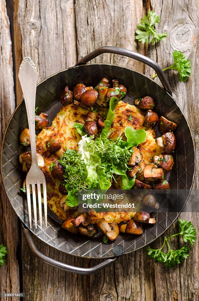 Fresh potato rosti in a pan with mushrooms and salad