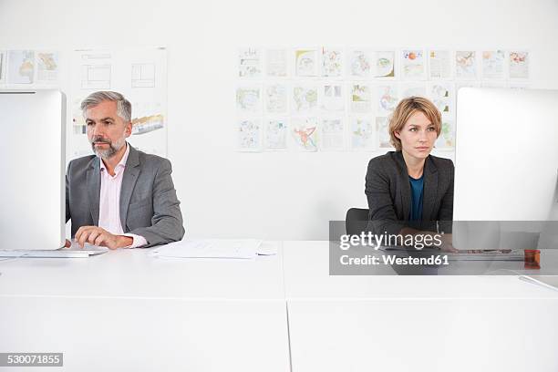 two colleagues working side by side in an office - two people side by side stock pictures, royalty-free photos & images