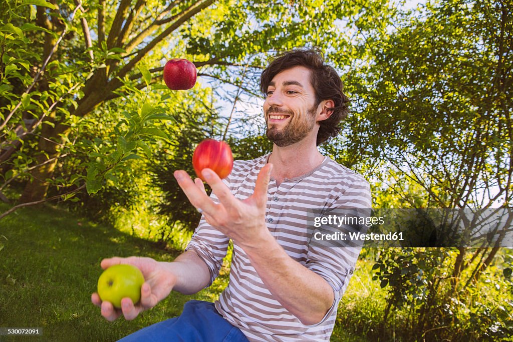 Man juggling with fruit in garden