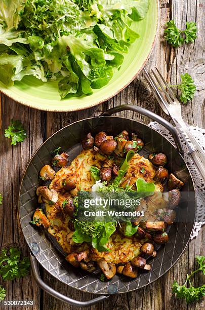 fresh potato rosti in a pan with mushrooms and salad on plate - ポテトケーキ ストックフォトと画像