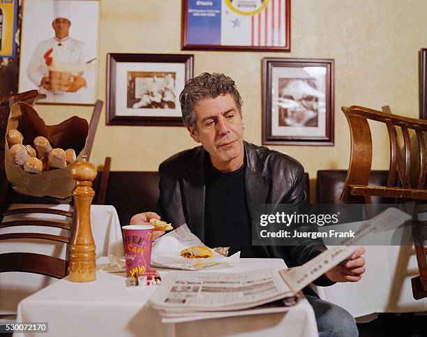 Chef Anthony Bourdain is photographed eating a sandwich and reading a newspaper in June 2003 at Brasserie Les Halles on Park Avenue in New York City.