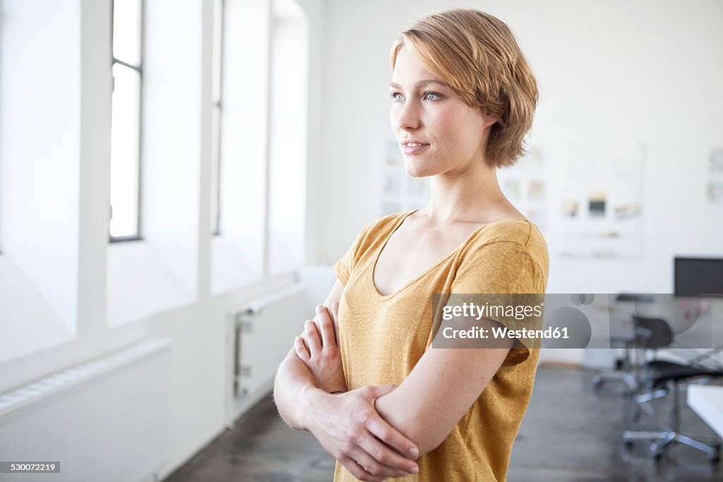 Portrait of young woman with crossed arms in a creative office