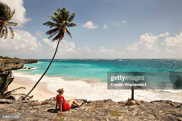caribbean, barbados, bottom bay, woman sitting at the coast - barbados beach stock pictures, royalty-free photos & images
