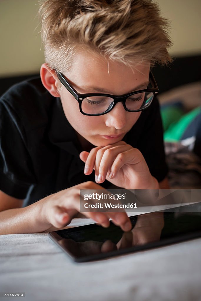 Portrait of a boy lying on bed using digital tablet