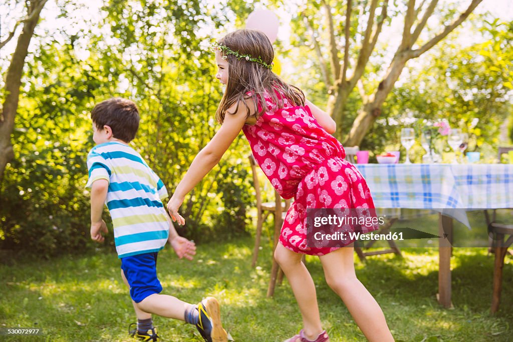 Boy and girl playing tag in garden