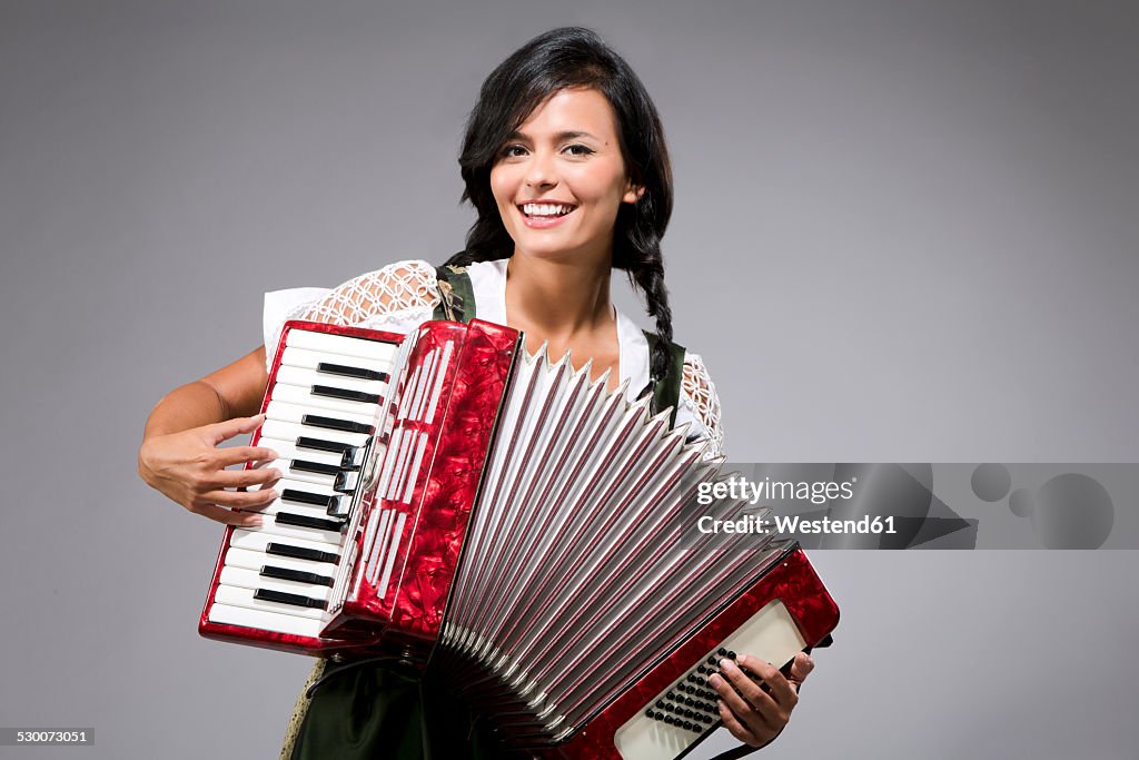 Portrait of smiling young woman playing accordion