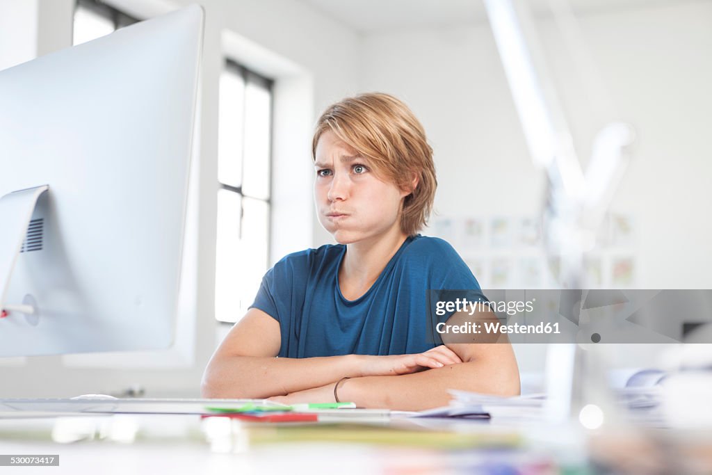 Portrait of young woman pouting a mouth at her desk in a creative office