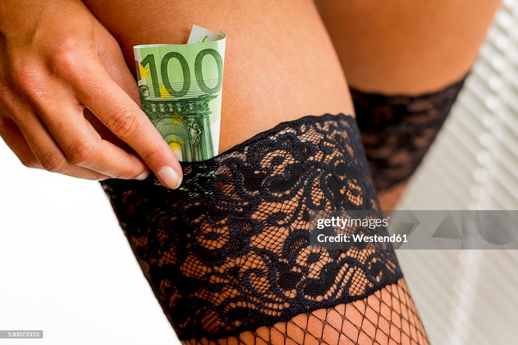 Young woman putting Euro note in her stocking