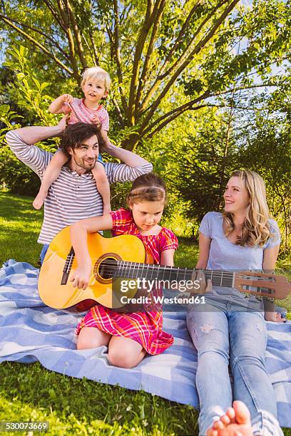 family on picnic blanket playing guitar - family vertical stock pictures, royalty-free photos & images