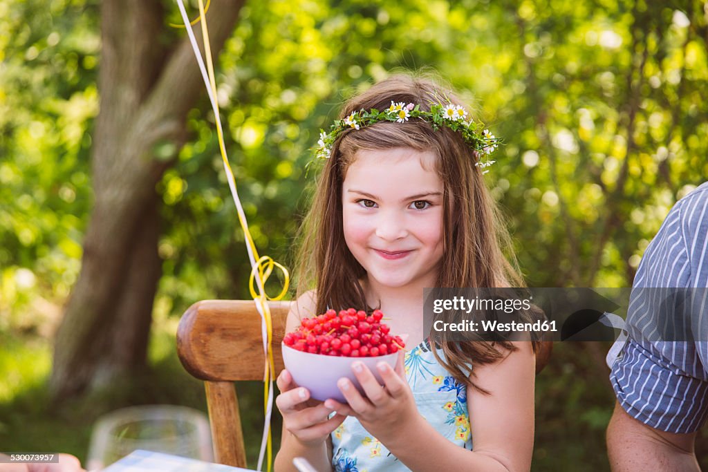 Girl holding bowl with redcurrants in garden