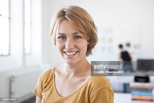 portrait of smiling young woman in a creative office - young blonde woman facing away photos et images de collection