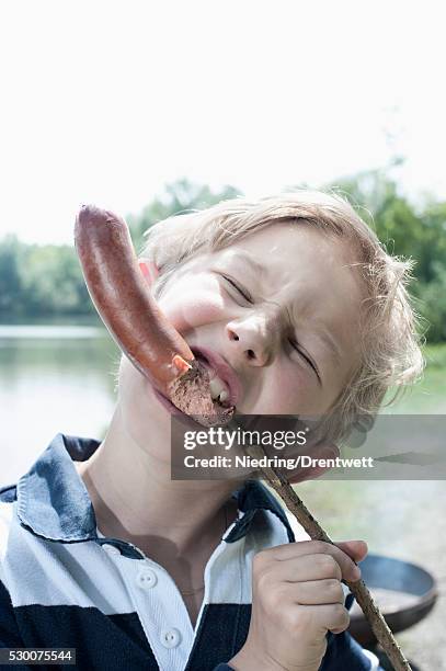 close-up of a boy eating sausage, bavaria, germany - biting ストックフォトと画像