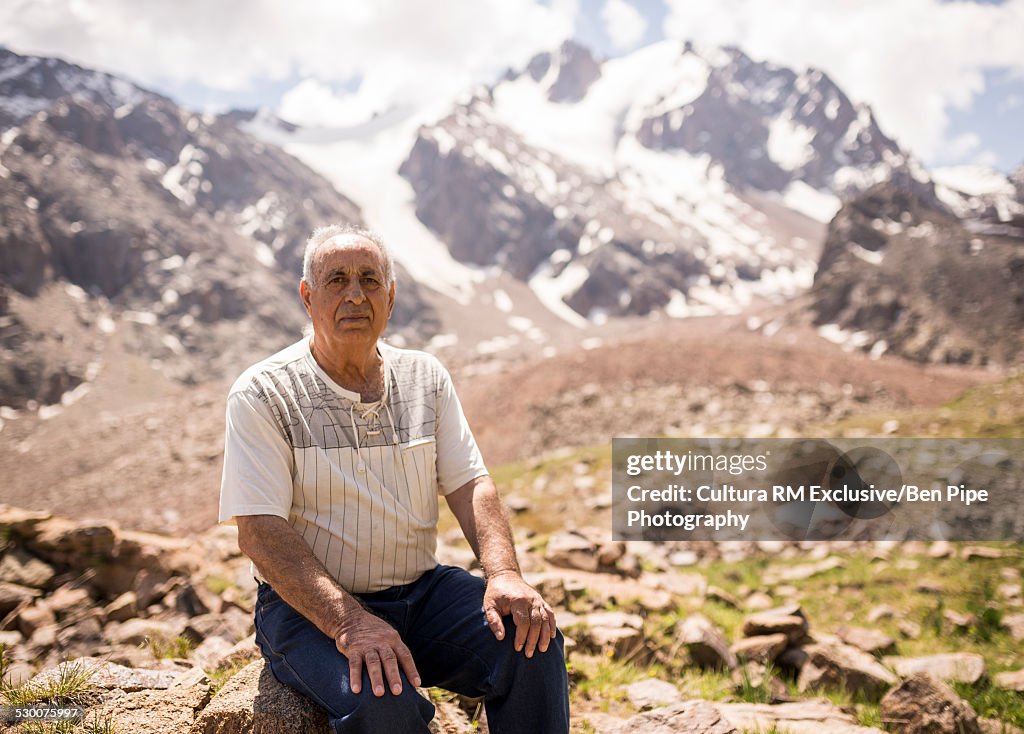 Portrait of senior man sitting on rock, Tian Shan Mountains, Almaty, Kazakhstan